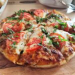 Close-up of a fresh Margherita pizza with tomatoes and basil. Perfect for Italian cuisine promotions.